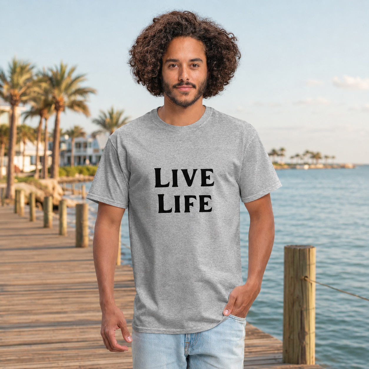 Man wearing the LIVE LIFE Coastal Standard men’s T-shirt on a waterfront boardwalk