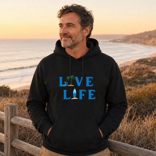 Man wearing the official LIVE LIFE hoodie at a coastal overlook during golden hour